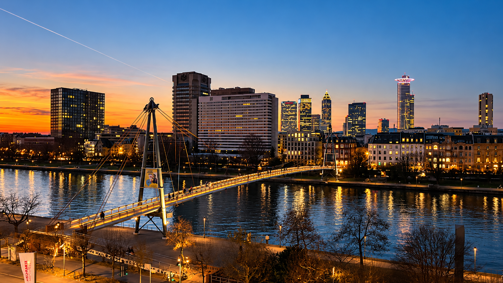 Fussgängerbrücke mit Skyline im Abendlicht